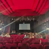 Widownia w Teatrze Palladium w Warszawie. Czerwone fotele i scena z ekranem czekają na widzów.