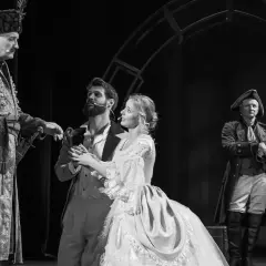Aktorzy w historycznych strojach na scenie. W centrum młoda para, obok nich starszy mężczyzna w bogatym stroju. To piękny **teatr u przyjaciół**.