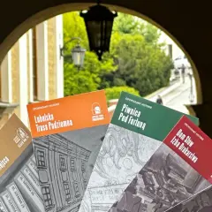 Książki o historii Lublina, m.in. "Lubelska Trasa Podziemna" i "Piwnica Pod Fortuną", prezentowane na tle bramy. Teatr NN Lublin zaprasza do odkrywania przeszłości.