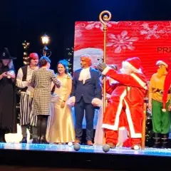 Aktorzy w strojach świątecznych i bajkowych na scenie, w tym Święty Mikołaj.