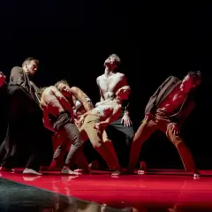 Tancerze Teatru Tańca Rozbark w dynamicznej choreografii na czerwonej scenie.
