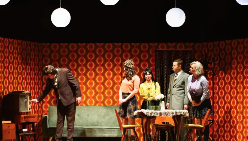 Scena z życia w polskich teatrach: mężczyzna przy starym telewizorze, kobiety w modnych strojach i elegancki pan.