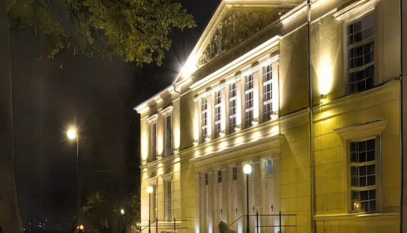 Elegancki budynek teatru w Jeleniej Górze nocą, oświetlony ciepłym światłem.