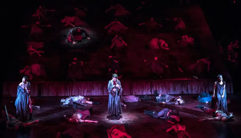 Scena z "Makbeta" w Teatrze Muzycznym Wrocław. Na scenie leżą martwi, stoi postać z dzieckiem.