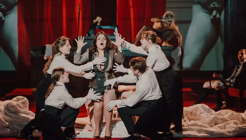 Kalisz teatr repertuar: scena z dramatycznym aktem, gdzie aktorka w centrum otoczona jest przez innych wykonawców.