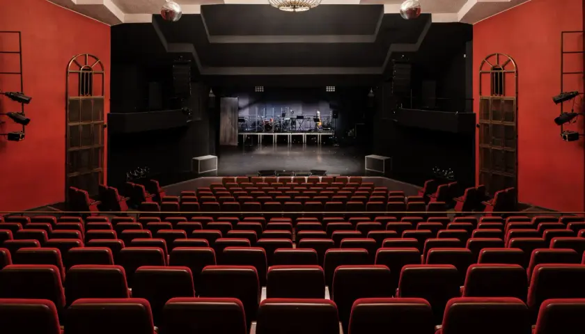 Widownia teatru na Targówku, z rzędami czerwonych foteli i sceną gotową na występ.
