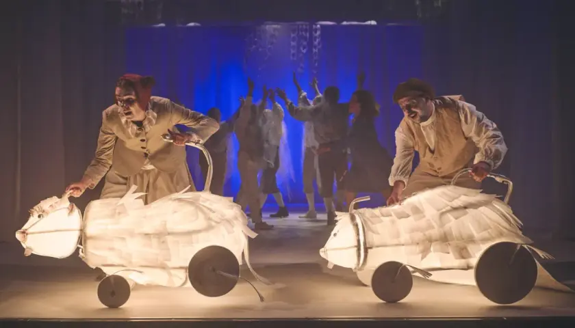 Aktorzy Teatru Lalki i Aktora Wałbrzych prowadzą świetliste, papierowe zwierzęta na scenie.