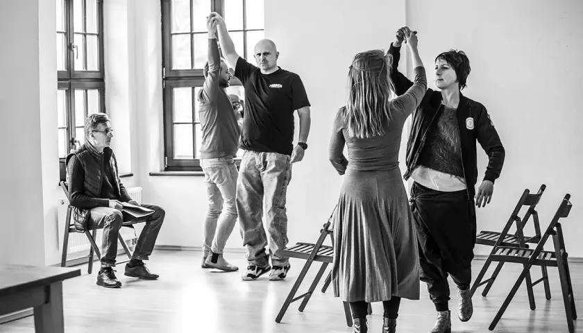 Grupa ludzi ćwiczy w sali, przygotowując się do spektaklu. To scena z życia **teatru polskiego w podziemiu**, gdzie pasja tworzy sztukę mimo trudności.