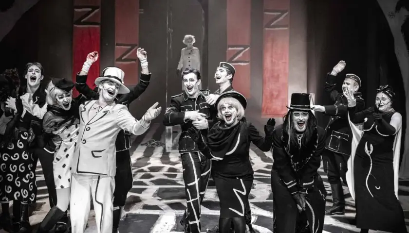Aktorzy w teatralnych strojach, z mocnym makijażem, na scenie. Spektakl z repertuaru Teatru Starego w Krakowie.