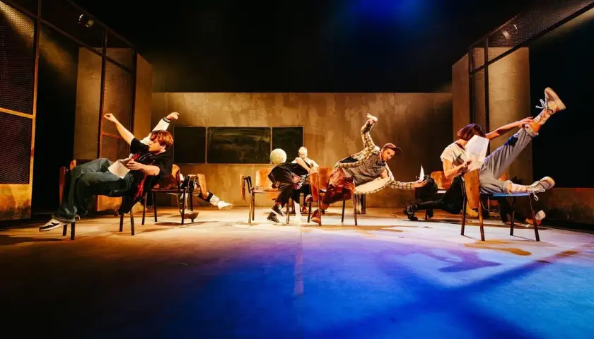 Aktorzy Teatru Lalek Pleciuga w dynamicznych pozach na scenie, unoszący się w powietrzu.