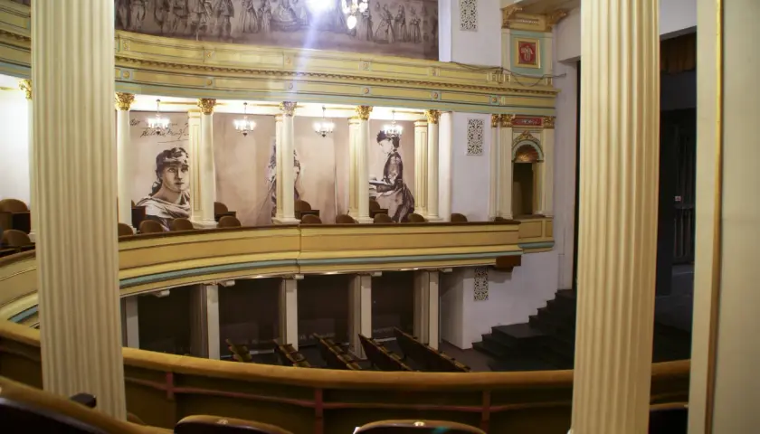 Wnętrze teatru im. H. Modrzejewskiej z portretami aktorek i malowidłem na ścianie.