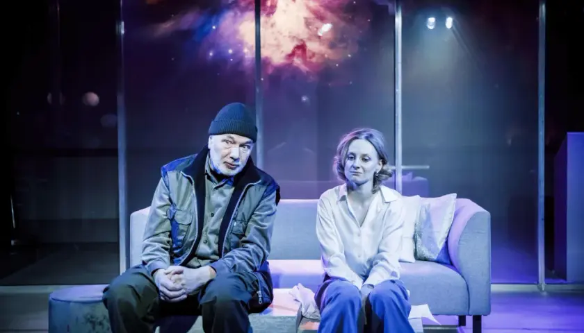 Para siedzi na kanapie w teatrze współczesnym na Mokotowie w Warszawie. Tło sceny to kosmiczna mgławica.