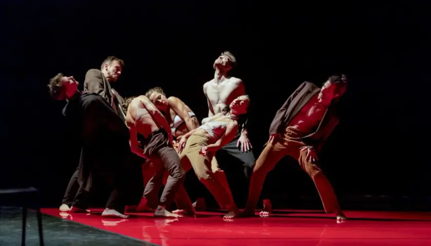 Tancerze Teatru Tańca Rozbark w dynamicznej choreografii na czerwonej scenie.