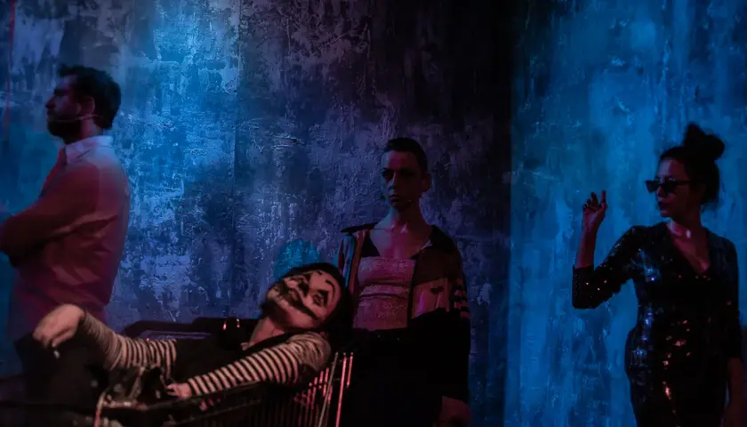 Scena z teatru Barakah. Aktor w wózku, klaun z makijażem, kobieta w cekinowej sukience i mężczyzna w białej koszuli.