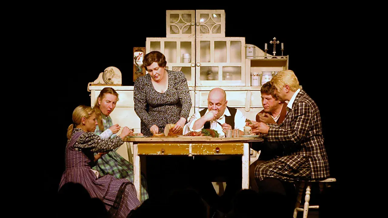 Scena z życia rodzinnego na stole obficie zastawionym jedzeniem. Sprawdź teatr Korez repertuar, by zobaczyć więcej takich przedstawień.