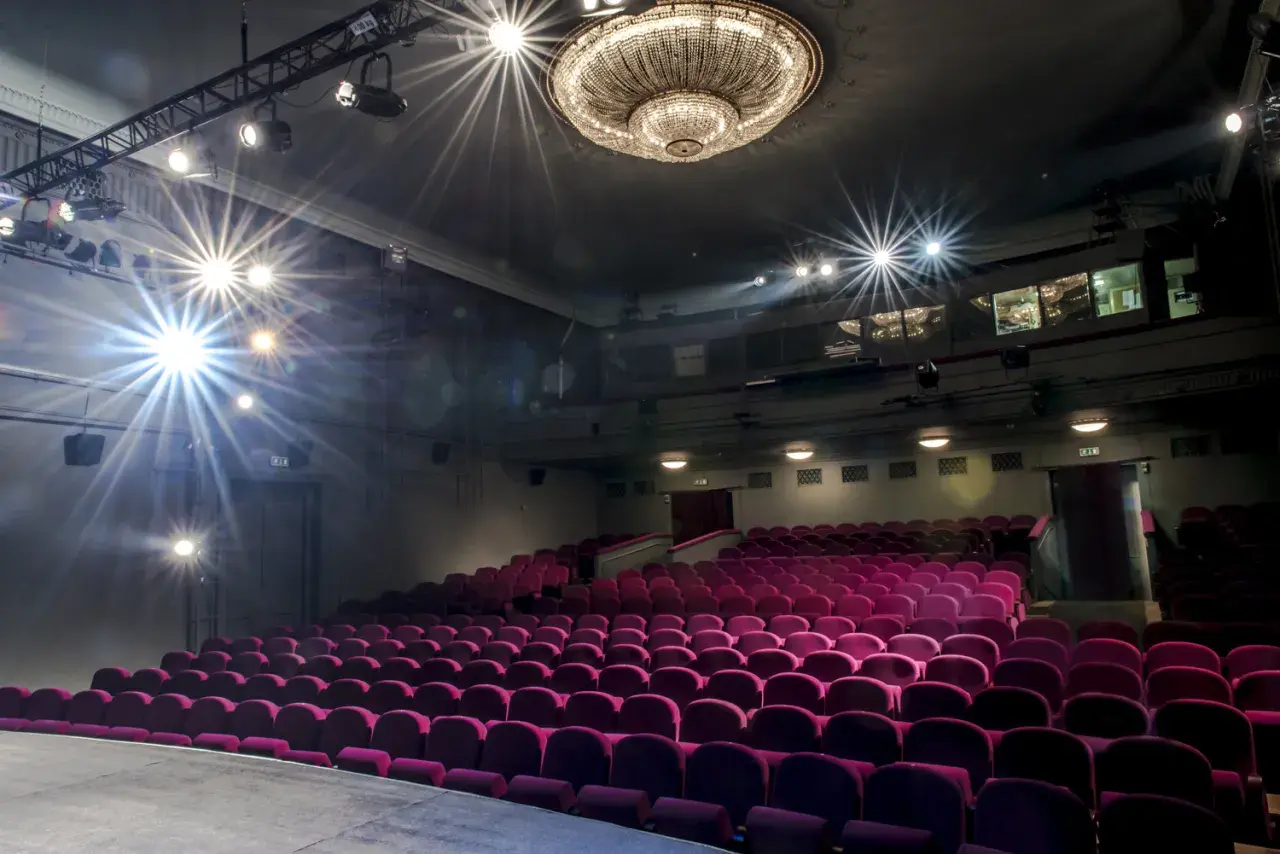 Puste fioletowe fotele w **Teatrze Studio im. Stanisława Ignacego Witkiewicza** czekają na widzów. Reflektory oświetlają scenę.