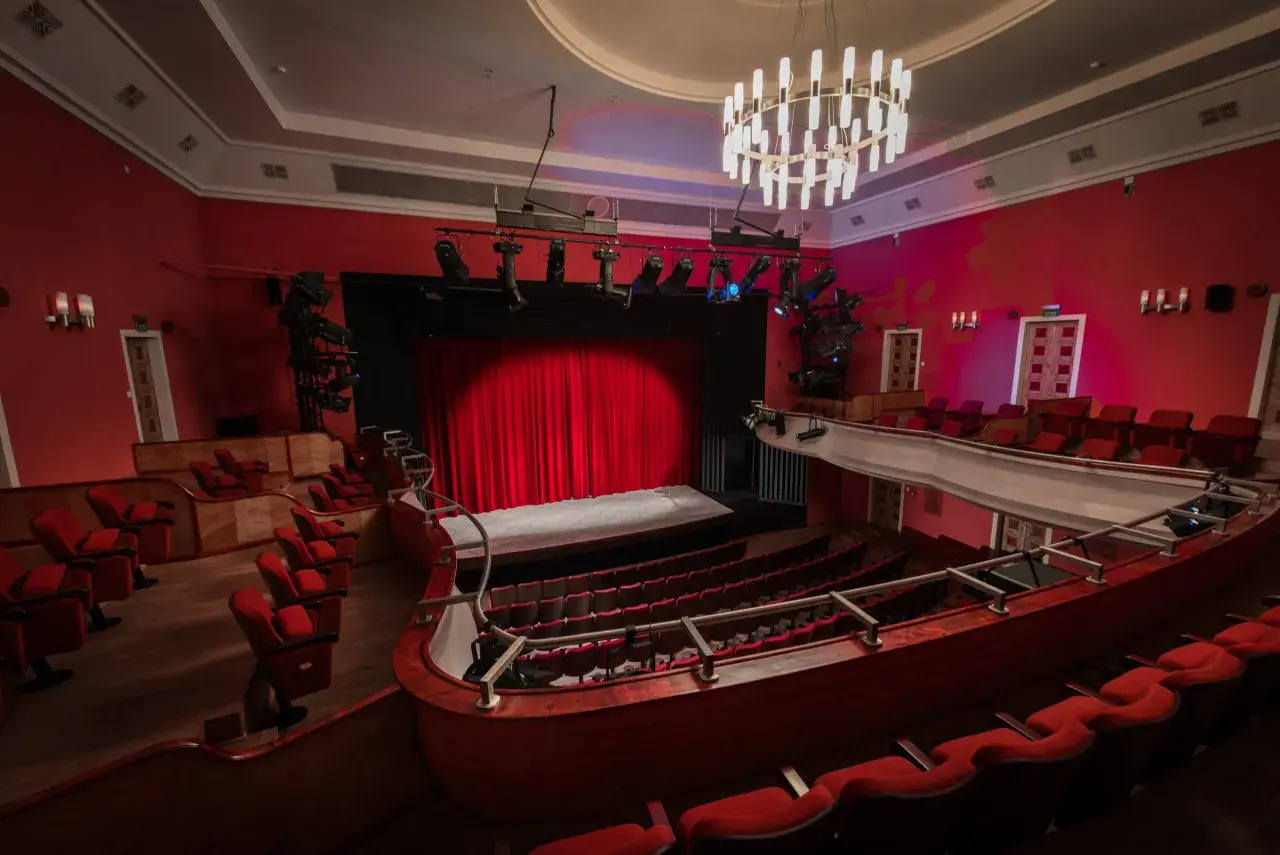 Widok na salę teatralną z czerwonymi fotelami i sceną. Teatr im. Stefana Jaracza w Łodzi czeka na widzów.