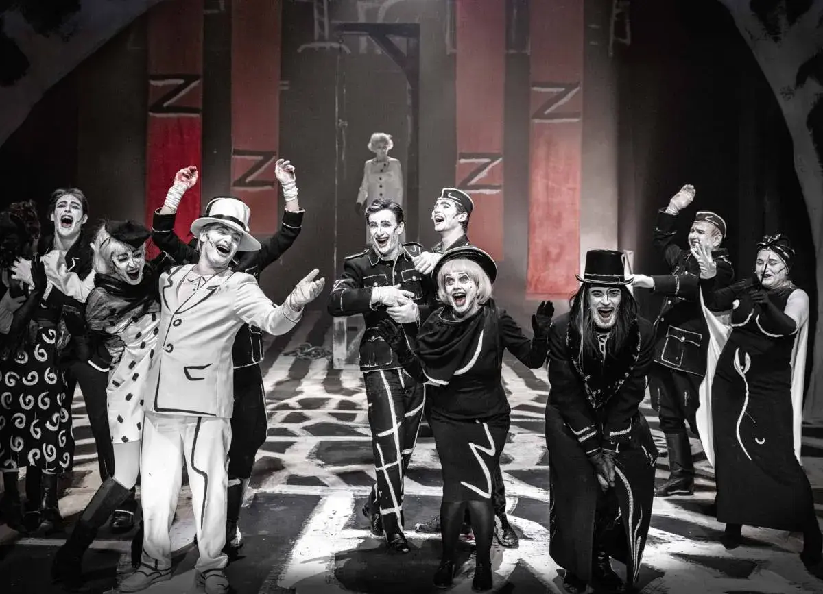 Aktorzy w teatralnych strojach, z mocnym makijażem, na scenie. Spektakl z repertuaru Teatru Starego w Krakowie.