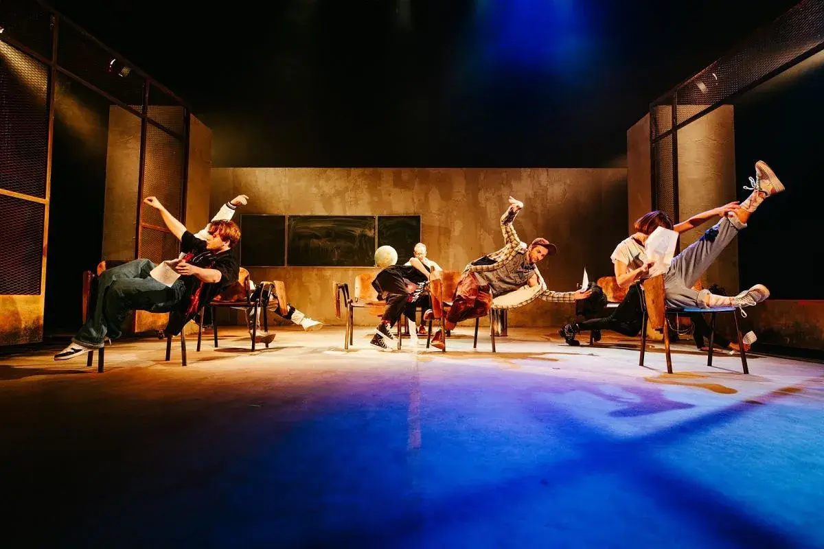 Aktorzy Teatru Lalek Pleciuga w dynamicznych pozach na scenie, unoszący się w powietrzu.