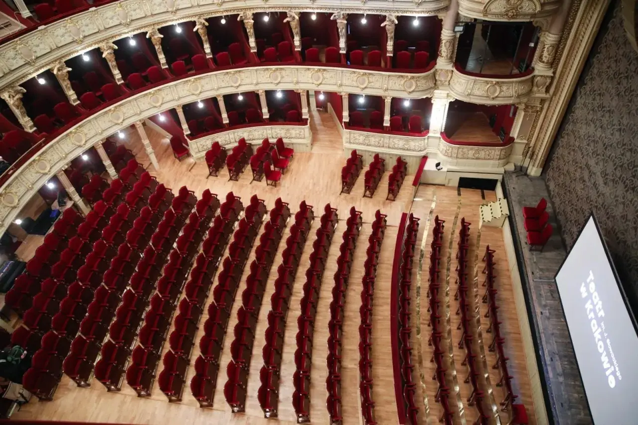 Widok z góry na bogato zdobione wnętrze Teatru im. Juliusza Słowackiego w Krakowie. Puste, czerwone fotele czekają na widzów, gotowe na kolejne spektakle.