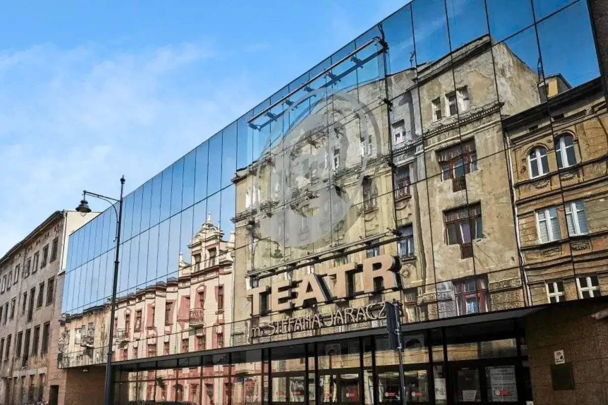 Nowoczesna fasada Teatru im. Stefana Jaracza w Łodzi odbija zabytkowe kamienice, tworząc fascynującą grę światła i historii.