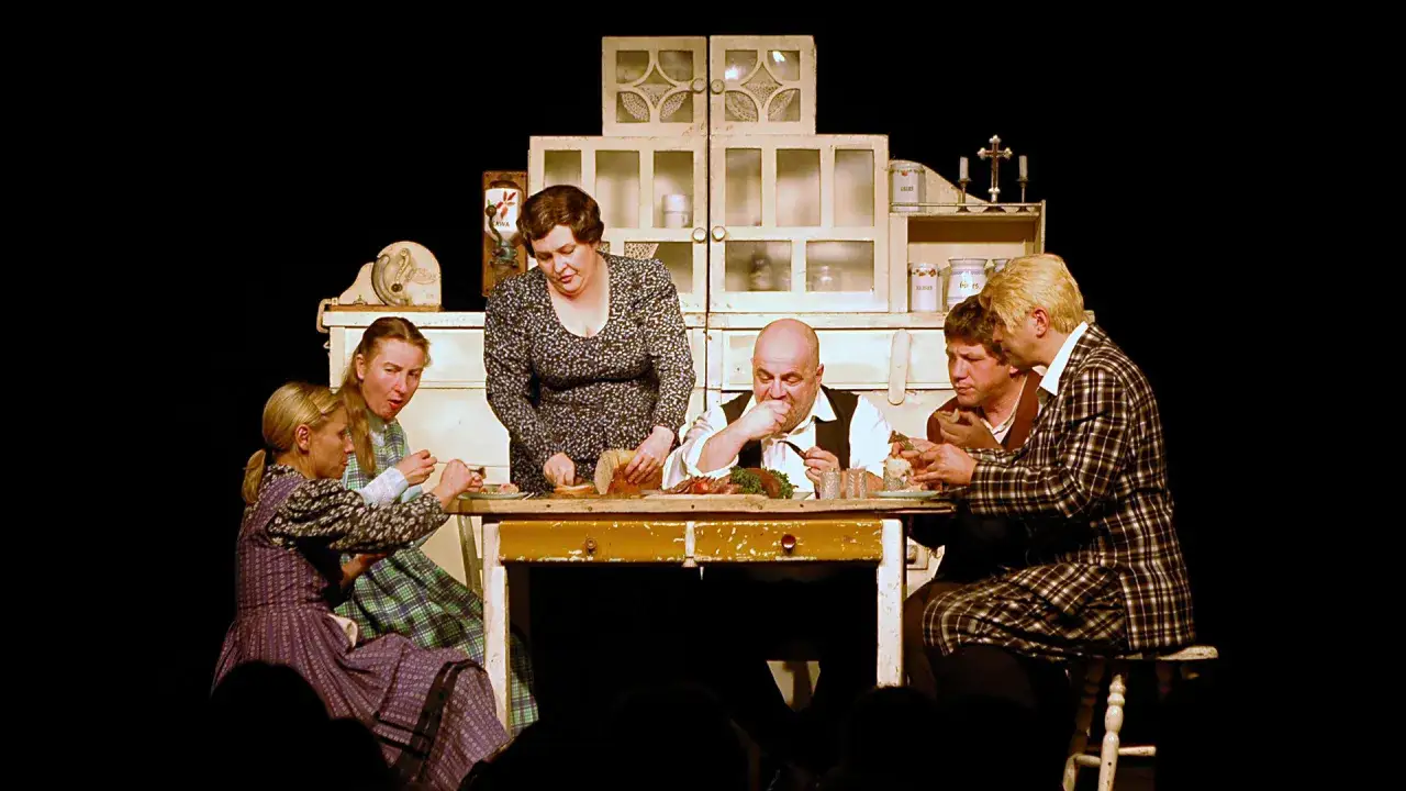 Scena z życia rodzinnego na stole obficie zastawionym jedzeniem. Sprawdź teatr Korez repertuar, by zobaczyć więcej takich przedstawień.