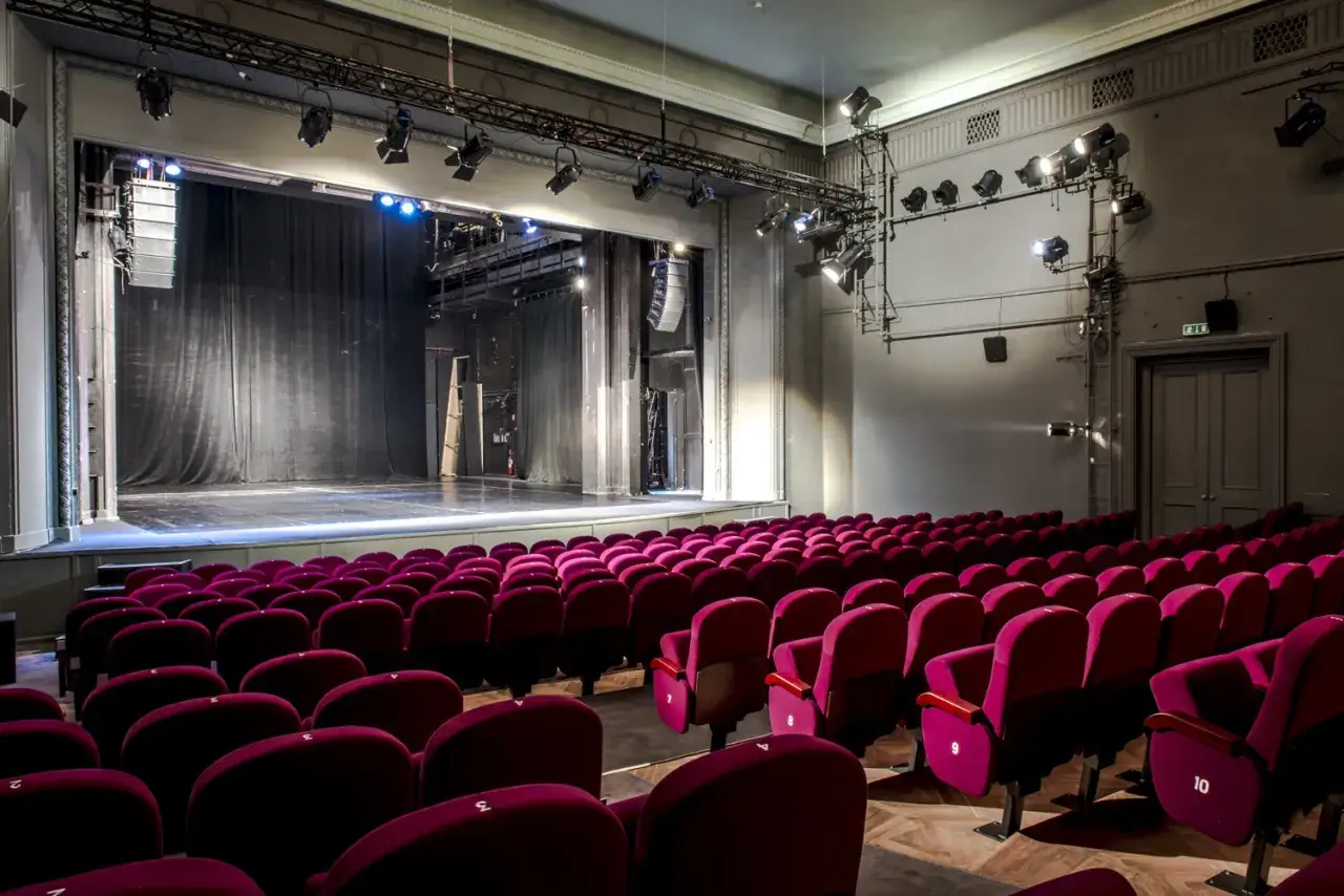 Puste fotele w teatrze Studio im. Stanisława Ignacego Witkiewicza czekają na widzów. Scena z czarną kurtyną i reflektorami gotowa na spektakl.