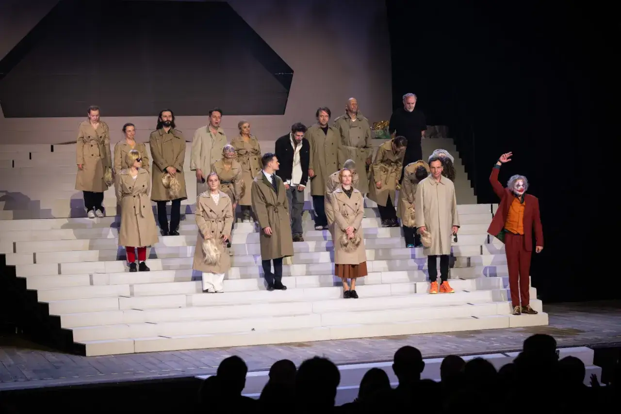 Aktorzy w płaszczach na schodach sceny Teatru Słowackiego. Na pierwszym planie postać w makijażu Jokera. Spektakle Teatru Słowackiego.