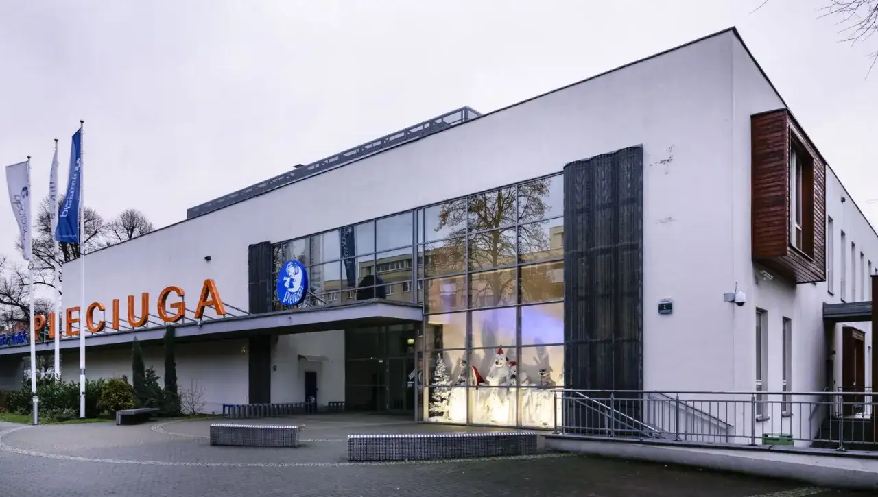 Teatr lalek Pleciuga zaprasza na magiczne przedstawienia. Na fasadzie widnieje nazwa teatru, a w witrynie świąteczna dekoracja.