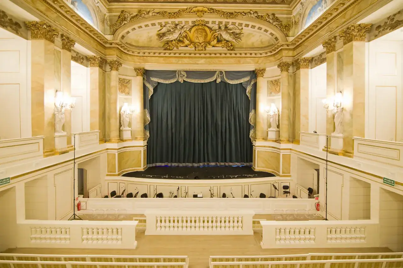 Elegancka sala operowa z kurtyną i lożami. Wnętrze zaprasza do odkrywania bogatego repertuaru opery królewskiej.
