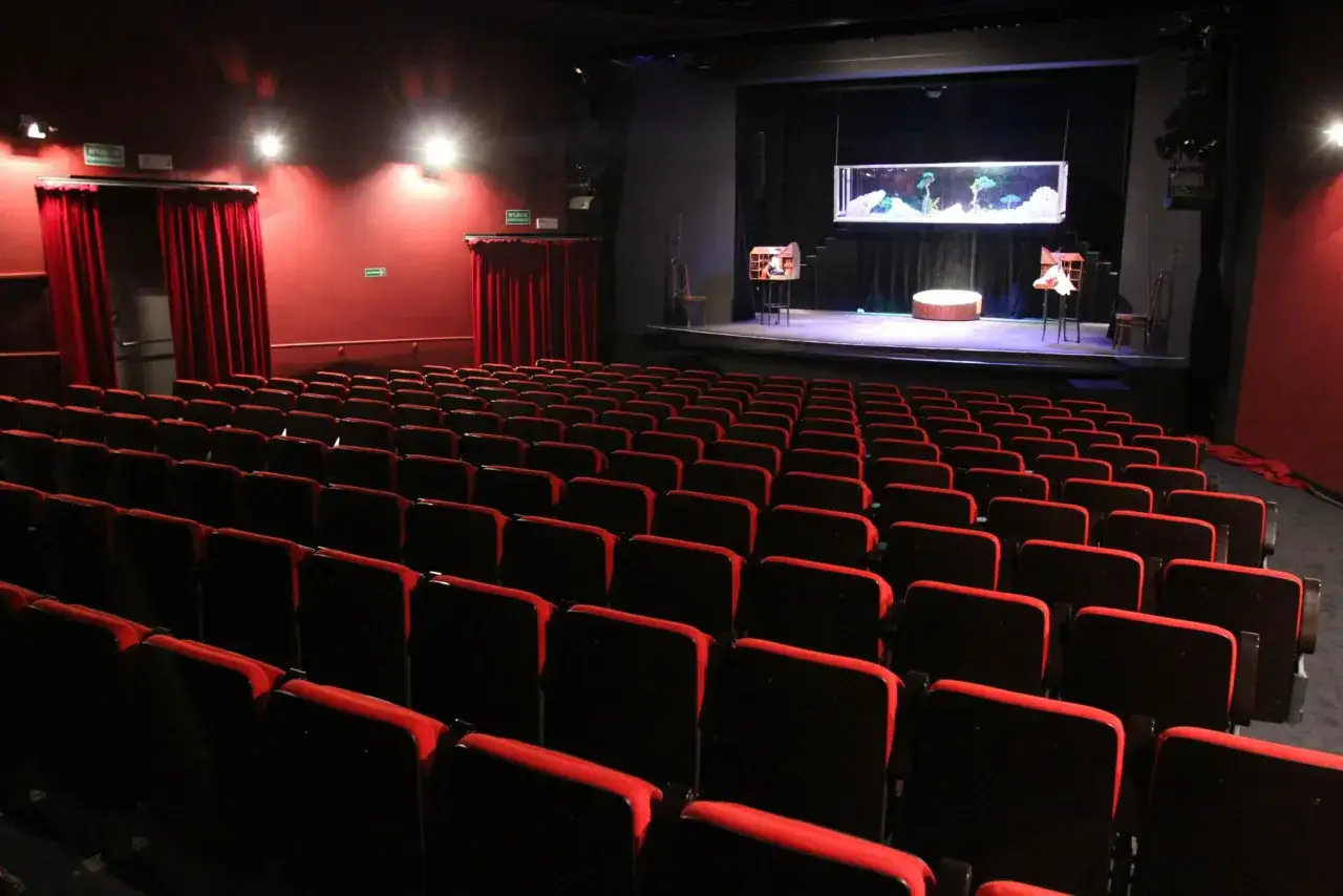 Puste czerwone fotele w teatrze lalek Banialuka im. Jerzego Zitzmana czekają na widzów. Na scenie akwarium i elementy scenografii.